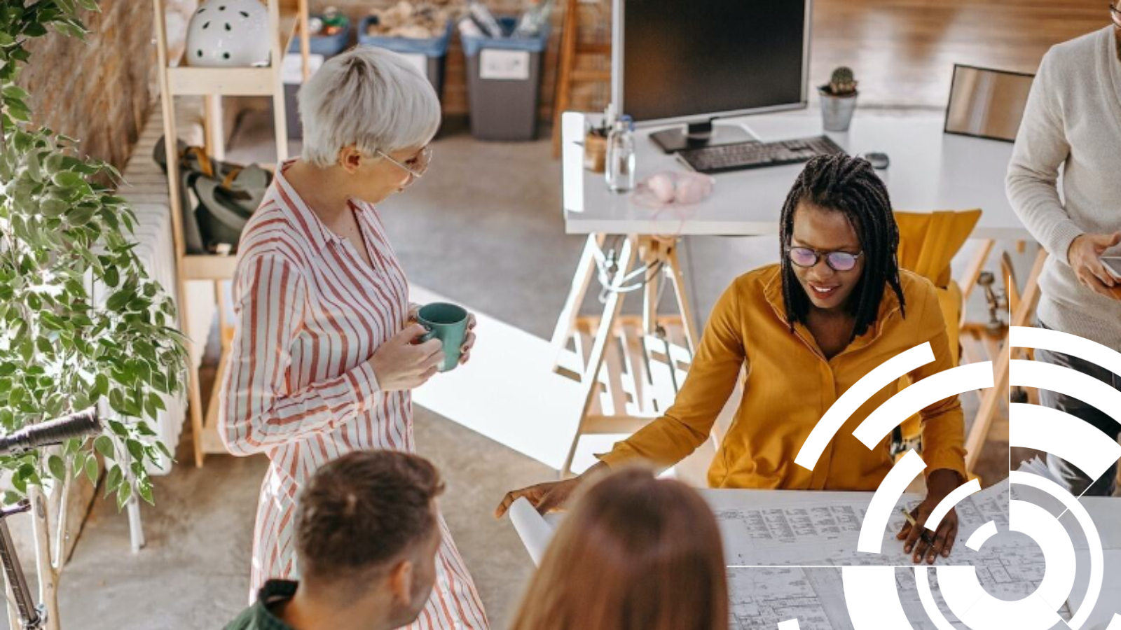 Photo of a small group of people in an office discussing a large piece of paper with printed text and diagrams on.