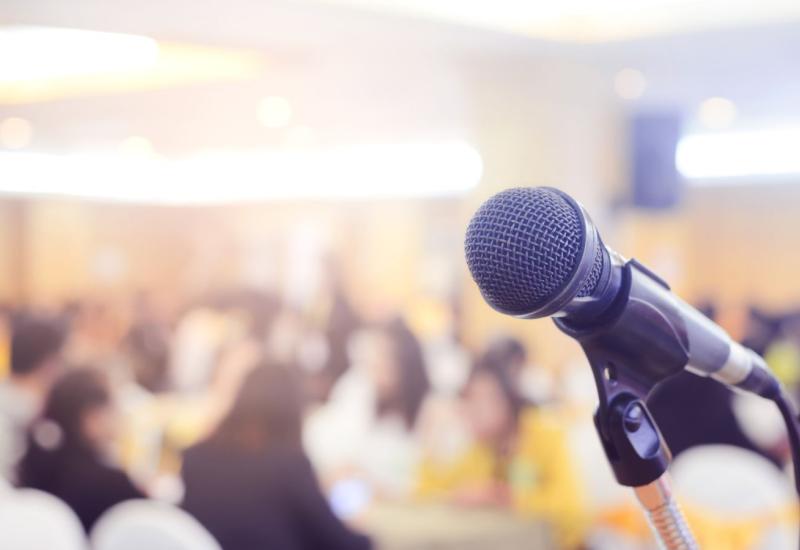 A microphone in front of a crowded meeting room