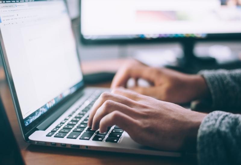 Photo of two hands typing on a laptop keyboard