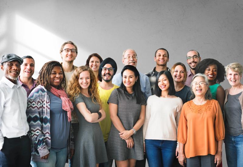A group of adults of different ages smiling together for a photograph.