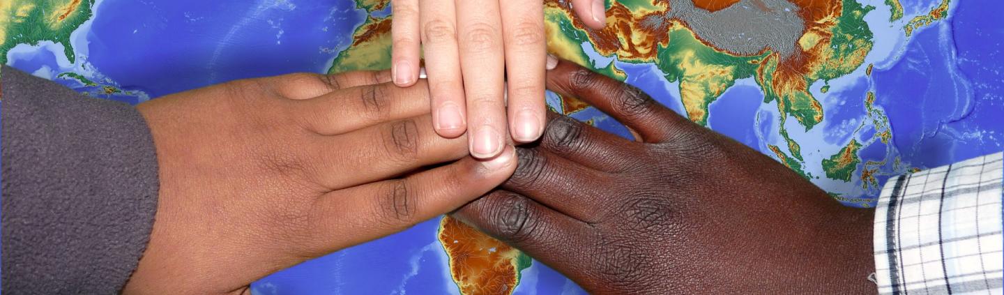 Hands joining on top of map of the world