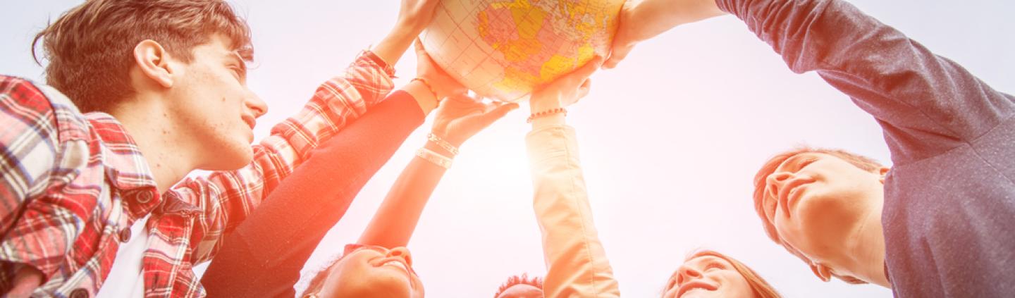 A group of young people holding up a model of the world