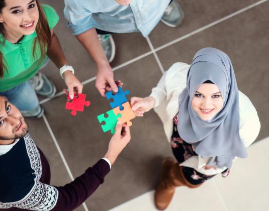 A group of people linking together jigsaw pieces representing integration