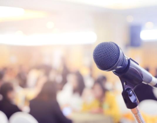 A microphone in front of a crowded meeting room