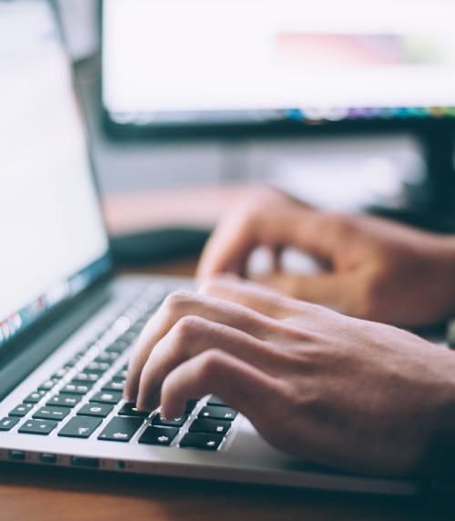 Photo of two hands typing on a laptop keyboard